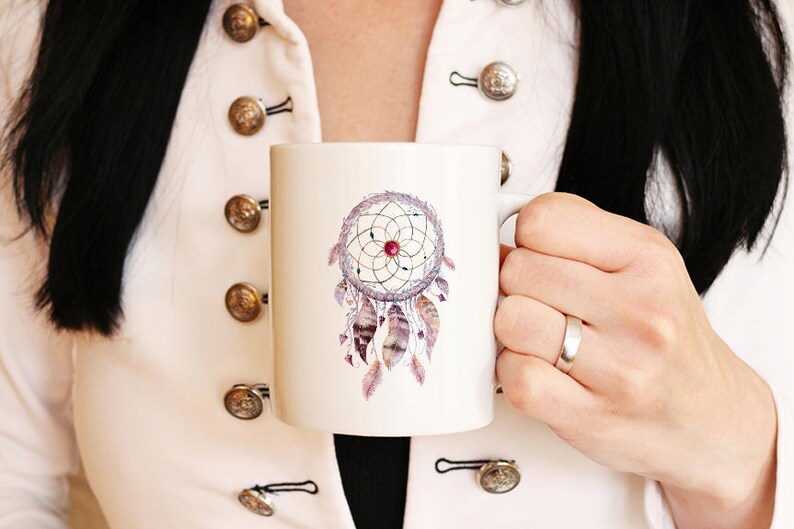 May include: White ceramic mug with a watercolor design of a dreamcatcher with purple, pink, and brown feathers. The dreamcatcher has a red bead in the center.