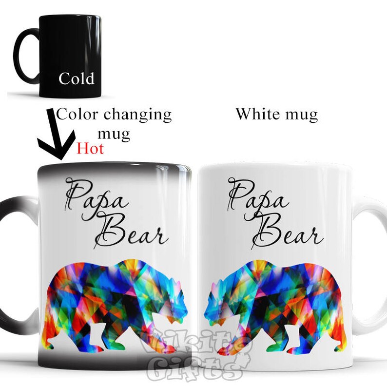 May include: A color-changing mug with a black exterior and a white interior. The mug features the text "Papa Bear" in black cursive script and a colorful bear design. The mug changes color when hot liquid is poured into it.