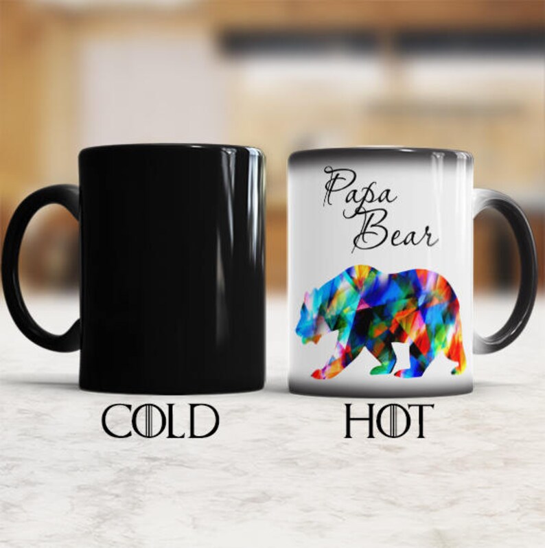 May include: A black and white color changing mug with the text "Papa Bear" and a colorful bear design. The mug is black when cold and reveals the design when hot.