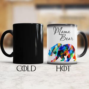 May include: A black ceramic mug with a color changing design. The mug is black when cold and shows a colorful bear with the text "Mama Bear" when hot.