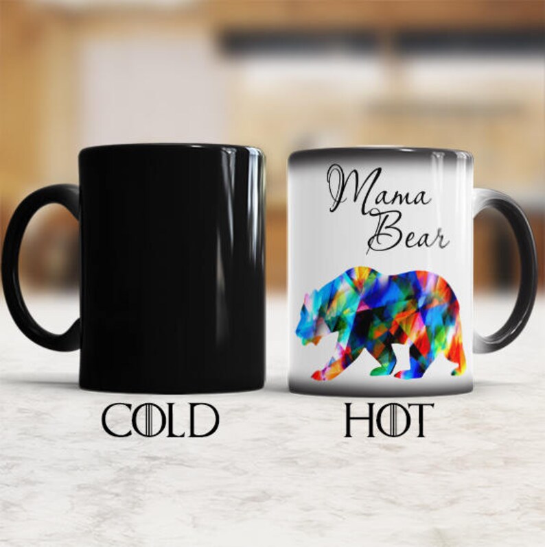 May include: A black ceramic mug with a color changing design. The mug is black when cold and shows a colorful bear with the text "Mama Bear" when hot.