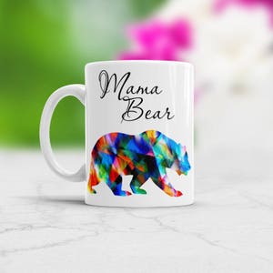 May include: White ceramic mug with a black and white graphic of a colorful bear and the text "Mama Bear".