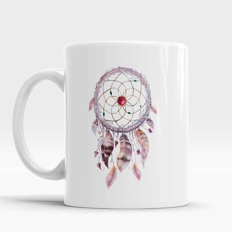 May include: White ceramic mug with a watercolor illustration of a dreamcatcher with feathers and a red gemstone in the center.