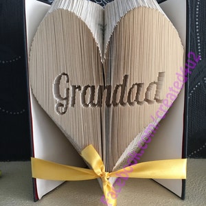 May include: A book folded into the shape of a heart with the word "Granddad" cut out of the pages. The book is tied with a yellow ribbon.