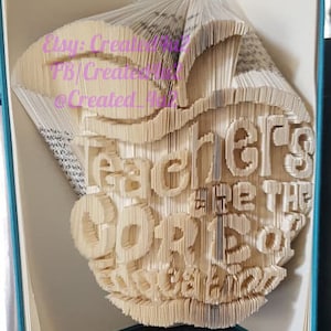 May include: A book folded into the shape of an apple with the words "Teachers are the  " and "Apples of our eyes" written on it.