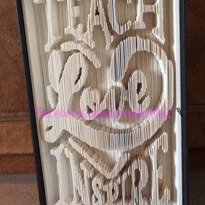 May include: A book art sculpture with the words "Teach Love Inspire" folded into the pages. The sculpture is displayed in a black frame.