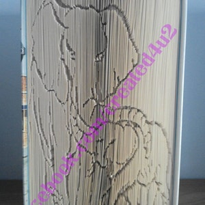 Pode incluir: Um livro dobrado na forma de dois elefantes, um maior que o outro. Os elefantes estão de frente um para o outro, com suas trombas se tocando. O livro é feito de papel branco e tem uma capa marrom claro.