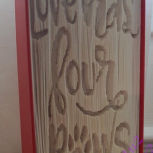 May include: A red book with the words "Love has four paws" carved into the pages. The book is decorated with a white ribbon with red polka dots.