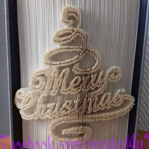 May include: A white book with a folded paper design of a Christmas tree with the words "Merry Christmas" in the center.