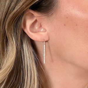 May include: Silver dangle earrings with a row of small clear stones.