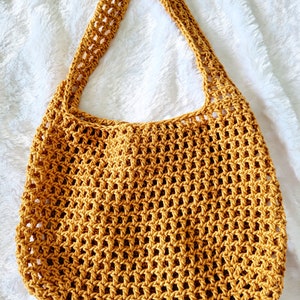 May include: A mustard yellow crocheted tote bag with a wide, open top and a single strap.