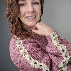 May include: A pink crocheted sweater with a white crocheted trim around the sleeves and shoulders.