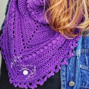 Peut inclure: Un ch&acirc;le au crochet violet vif fait &agrave; la main, avec un bord festonn&eacute;. Le ch&acirc;le pr&eacute;sente un motif ajour&eacute; et est pr&eacute;sent&eacute; sur une veste en jean. Le texte "Flo's Crafty Crochet" est visible sur le ch&acirc;le.