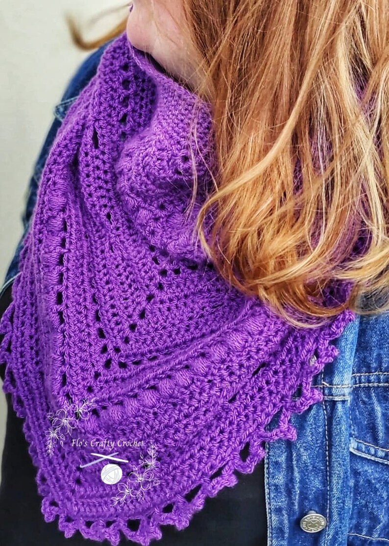 Peut inclure: Un ch&acirc;le au crochet violet vif fait &agrave; la main, avec un bord festonn&eacute;. Le ch&acirc;le pr&eacute;sente un motif ajour&eacute; et est pr&eacute;sent&eacute; sur une veste en jean. Le texte "Flo's Crafty Crochet" est visible sur le ch&acirc;le.