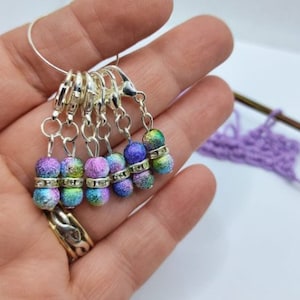 Pode incluir: Conjunto de seis marcadores de ponto coloridos com anéis prateados e strass transparentes. Os marcadores são iridescentes e têm um acabamento salpicado.