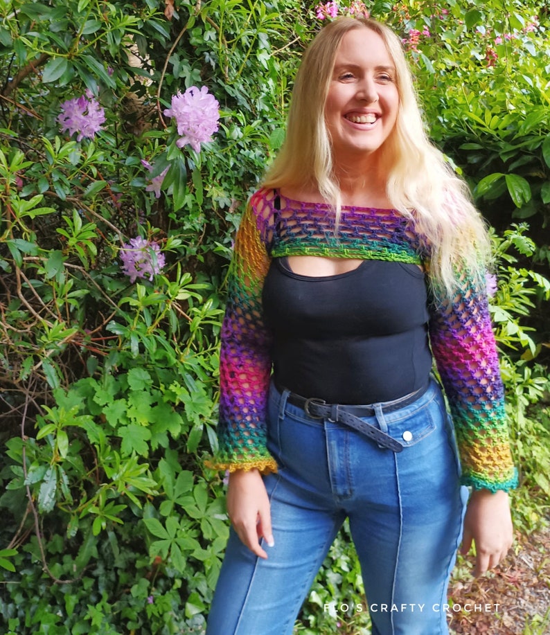 Peut inclure: Un haut en crochet arc-en-ciel &agrave; manches longues avec une d&eacute;coupe. Le haut est port&eacute; sur un d&eacute;bardeur noir et un jean bleu.