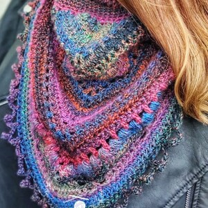 Peut inclure: Un ch&acirc;le en crochet fait main de forme triangulaire, aux couleurs vives : violet, bleu, orange et vert. Le ch&acirc;le pr&eacute;sente un motif textur&eacute; avec une bordure festonn&eacute;e, parfait pour ajouter une touche artisanale &agrave; toute tenue.