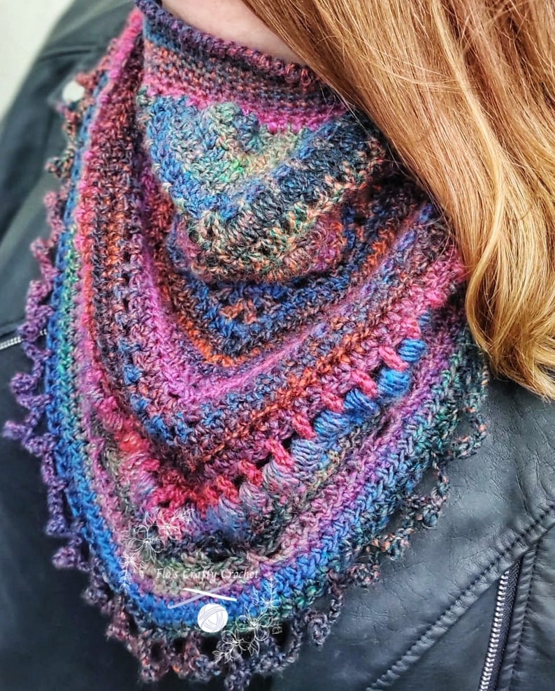 Peut inclure: Un ch&acirc;le en crochet fait main de forme triangulaire, aux couleurs vives : violet, bleu, orange et vert. Le ch&acirc;le pr&eacute;sente un motif textur&eacute; avec une bordure festonn&eacute;e, parfait pour ajouter une touche artisanale &agrave; toute tenue.