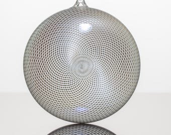 May include: A silver Christmas ornament with a swirling, geometric pattern.