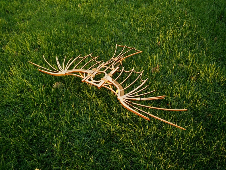 May include: A wooden model of a bird with outstretched wings. The model is made of thin strips of wood and has a delicate, intricate design.