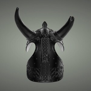 Puede incluir: Un casco vikingo negro con cuernos y dise&ntilde;os intrincados de nudos. El casco est&aacute; hecho de metal y tiene un acabado mate.