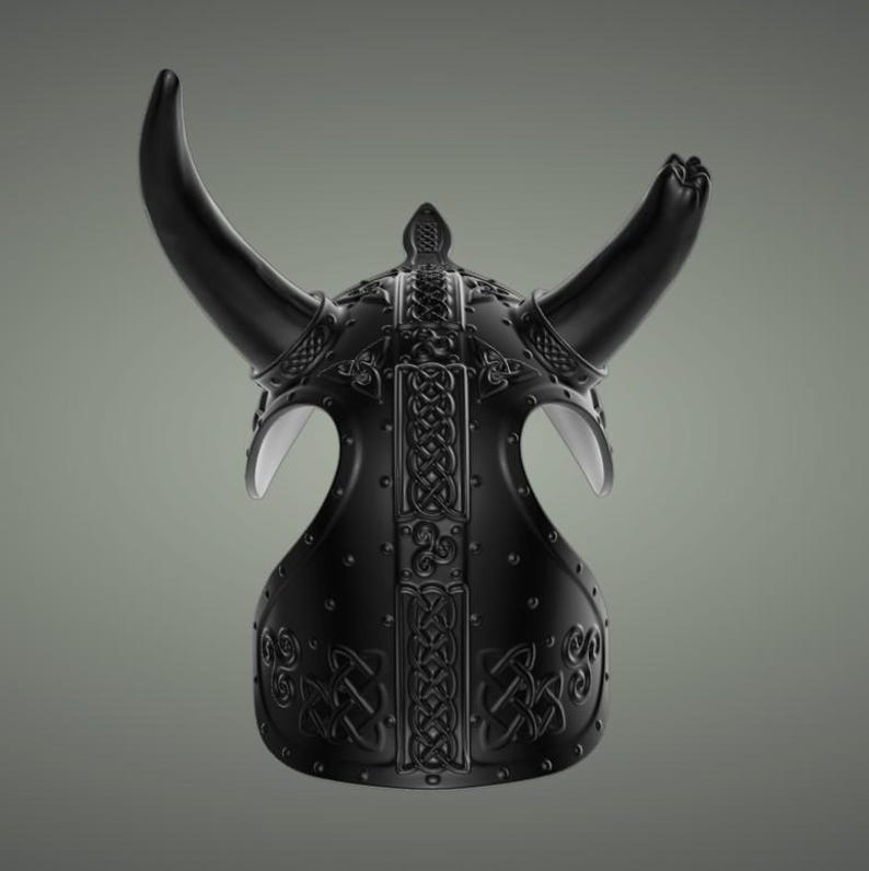 Puede incluir: Un casco vikingo negro con cuernos y dise&ntilde;os intrincados de nudos. El casco est&aacute; hecho de metal y tiene un acabado mate.