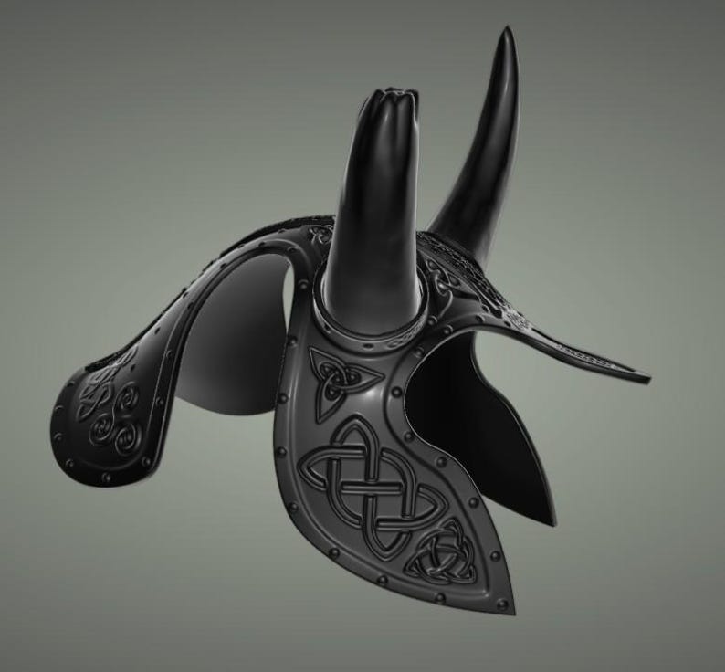 Puede incluir: Un casco negro con cuernos y dise&ntilde;os intrincados de nudos celtas. El casco est&aacute; hecho de metal y tiene una superficie texturizada.