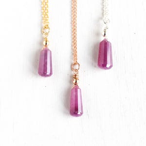 Könnte beinhalten: Drei zarte Halsketten mit rosafarbenen Edelstein-Anhängern. Jede Halskette hat einen anderen Ketten-Stil: Gold, Roségold und Silber.