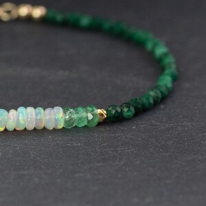 Puede incluir: Una delicada pulsera de cuentas que presenta una secuencia de rondeles de &oacute;palo blanco iridiscente, seguidos de peque&ntilde;as cuentas de esmeralda verde facetadas y una cuenta espaciadora dorada, terminada con un cierre dorado en el extremo.
