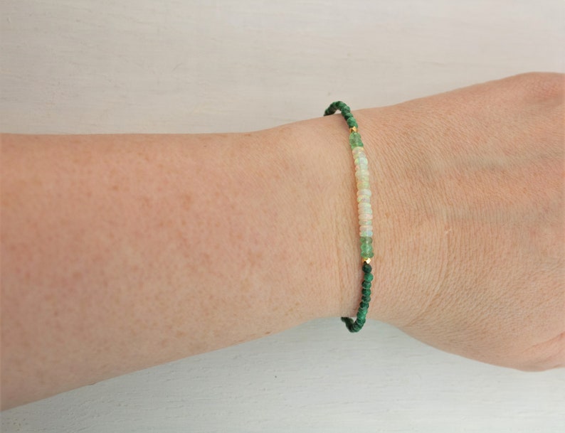 Puede incluir: Una pulsera delicada con peque&ntilde;as cuentas redondas de color verde oscuro, intercaladas con una secci&oacute;n central de cuentas blancas p&aacute;lidas e iridiscentes. El dise&ntilde;o incluye diminutas cuentas espaciadoras de metal dorado que separan los segmentos.