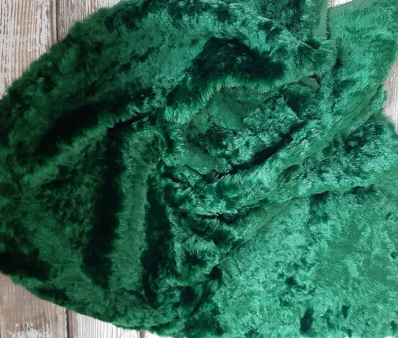 May include: A close-up of a deep green faux fur fabric. The fabric has a soft, plush texture and is perfect for crafting projects.