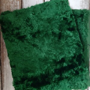 May include: Two pieces of dark green faux fur fabric. The fabric has a soft, plush texture.