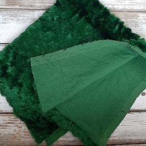 May include: A green velvet fabric with a fuzzy texture and a plain green fabric backing. The two fabrics are sewn together along the edges.