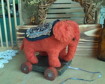 Elephant on wheels  Red plush elephant with a blanket on wheels Antique elephant