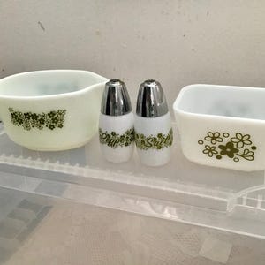 以下が含まれることがあります： クリーマー、塩コショウ入れ2つ、長方形の小皿がセットになったヴィンテージキッチンセット。白い食器にはグリーンの花柄が施されています。塩コショウ入れはシルバーの蓋が付いています。