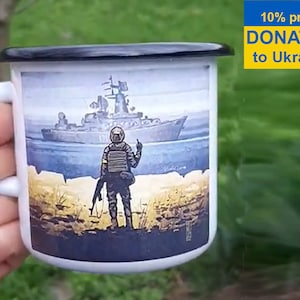 May include: White enamel mug with a black rim and handle. The mug features a graphic of a soldier standing on a beach with a warship in the background. The text "10% profit DONATED to Ukraine" is printed on the mug.