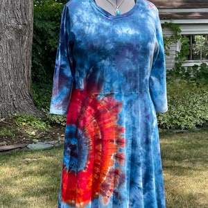 May include: A blue and orange tie-dye dress with a round neckline and 3/4 sleeves. The dress is made of a soft, comfortable fabric and has a flowy, A-line silhouette.