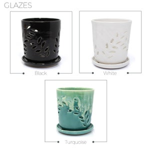 May include: Three ceramic planter pots with drainage holes and a leaf design. The pots are in black, white, and turquoise.