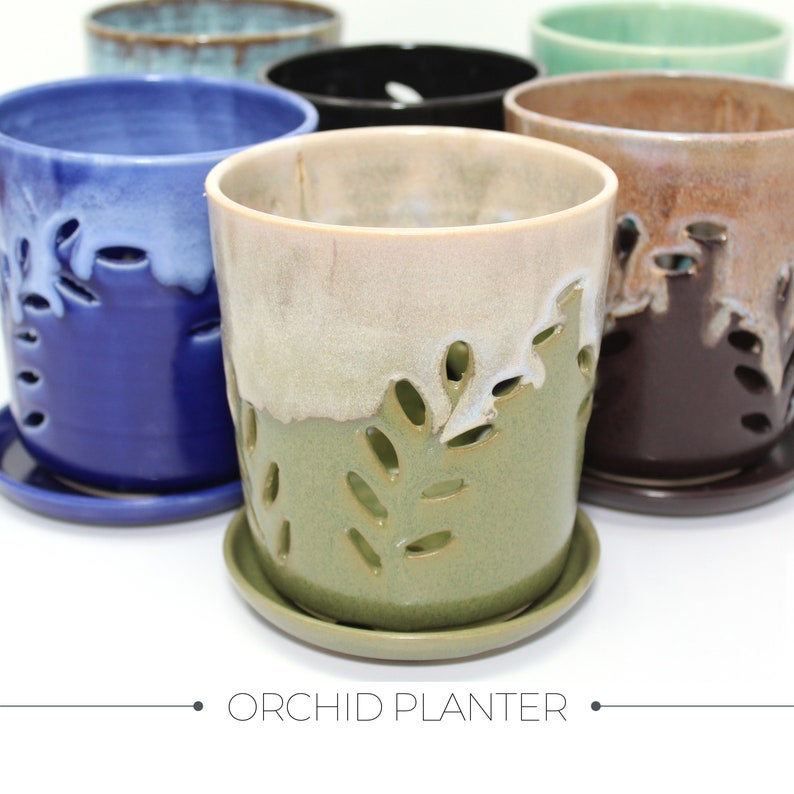 May include: Assortment of ceramic orchid planters in various colours, including blue, green, brown, and beige. Each planter features a unique leaf design and a drainage hole.