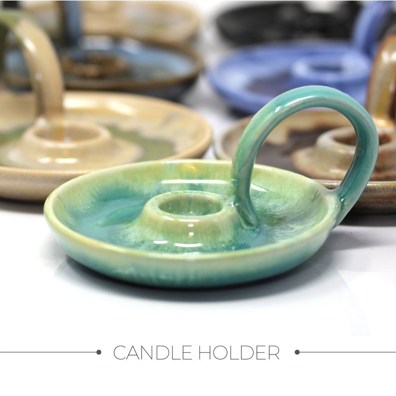 May include: A teal green ceramic candle holder with a handle. The holder has a glazed finish and a ring to hold a candle.