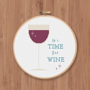 May include: White embroidery hoop with a red wine glass and the text "It's TIME for WINE" in blue and white.