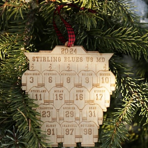 May include: A wooden hockey ornament with the text "Stirling Blues U9 MD" and the game time "20:24". The ornament features a team roster with player names and jersey numbers.