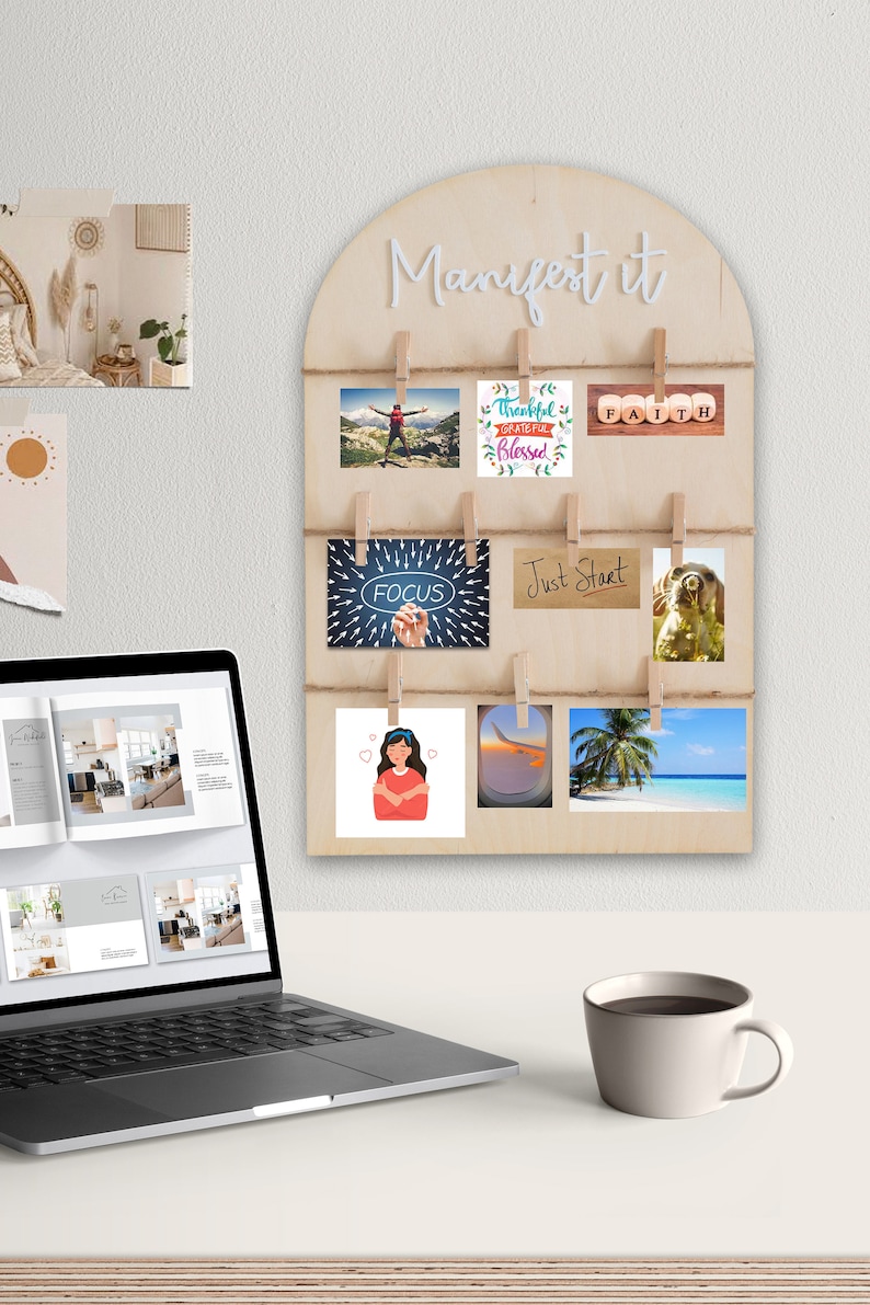 May include: A wooden wall decor with a white arch and the text "Manifest it" at the top. The arch has clips holding various cards with inspirational messages and images, including "Thankful Grateful Blessed", "Faith", "Focus", "Just Start", and a picture of a tropical beach.