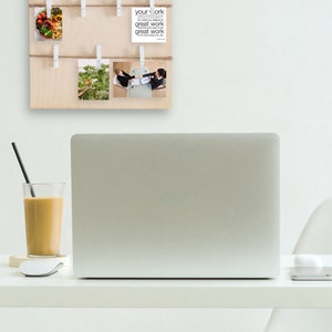 May include: A wooden board with the word "Goals" written in white letters. The board has multiple clothespins holding photos and a card with the text "Your work is your work do what you believe in great work comes from great work love what you do".
