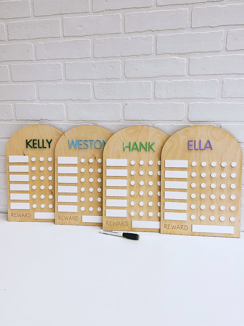 May include: Four wooden reward charts with the names Kelly, Weston, Hank, and Ella written in colorful letters. Each chart has a white space for a reward and a grid of white circles for tracking progress.