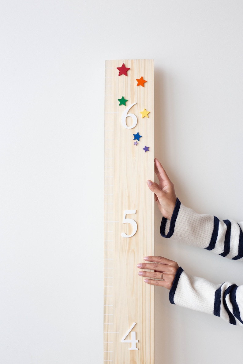 Puede incluir: Un gr&aacute;fico de crecimiento de madera con los n&uacute;meros blancos 4, 5 y 6. El gr&aacute;fico est&aacute; decorado con estrellas de colores. Una mano est&aacute; llegando hacia el gr&aacute;fico.