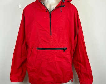 Peut inclure: Une veste anorak rouge vif avec une fermeture éclair et une poche noires. La veste a un cordon de serrage à la capuche et à l'ourlet. L'anorak est présenté sur un mannequin blanc.