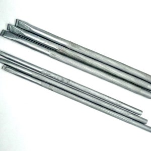 Puede incluir: Conjunto de cinco herramientas de metal plateado con mangos texturados. Las herramientas son de diferentes longitudes y tienen puntas de diferentes formas.