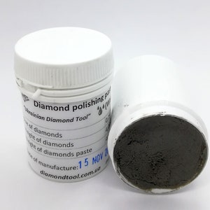 May include: A white jar with a black label that reads "Diamond polishing paste Ukrainian Diamond Tool" and a date of manufacture of "15 NOV 20". The jar is open and the grey paste inside is visible.
