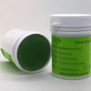 May include: A white jar with a green lid containing a green diamond polishing paste. The jar has a label that reads "Diamond polish" and "Ukrainian Diamond Tool". The label also includes the text "Size of diamonds", "Weight of diamonds", "Weight of diamonds paste", and "Date of manufacture: 2114". The label also includes the website address "diamondtool.com.ua".